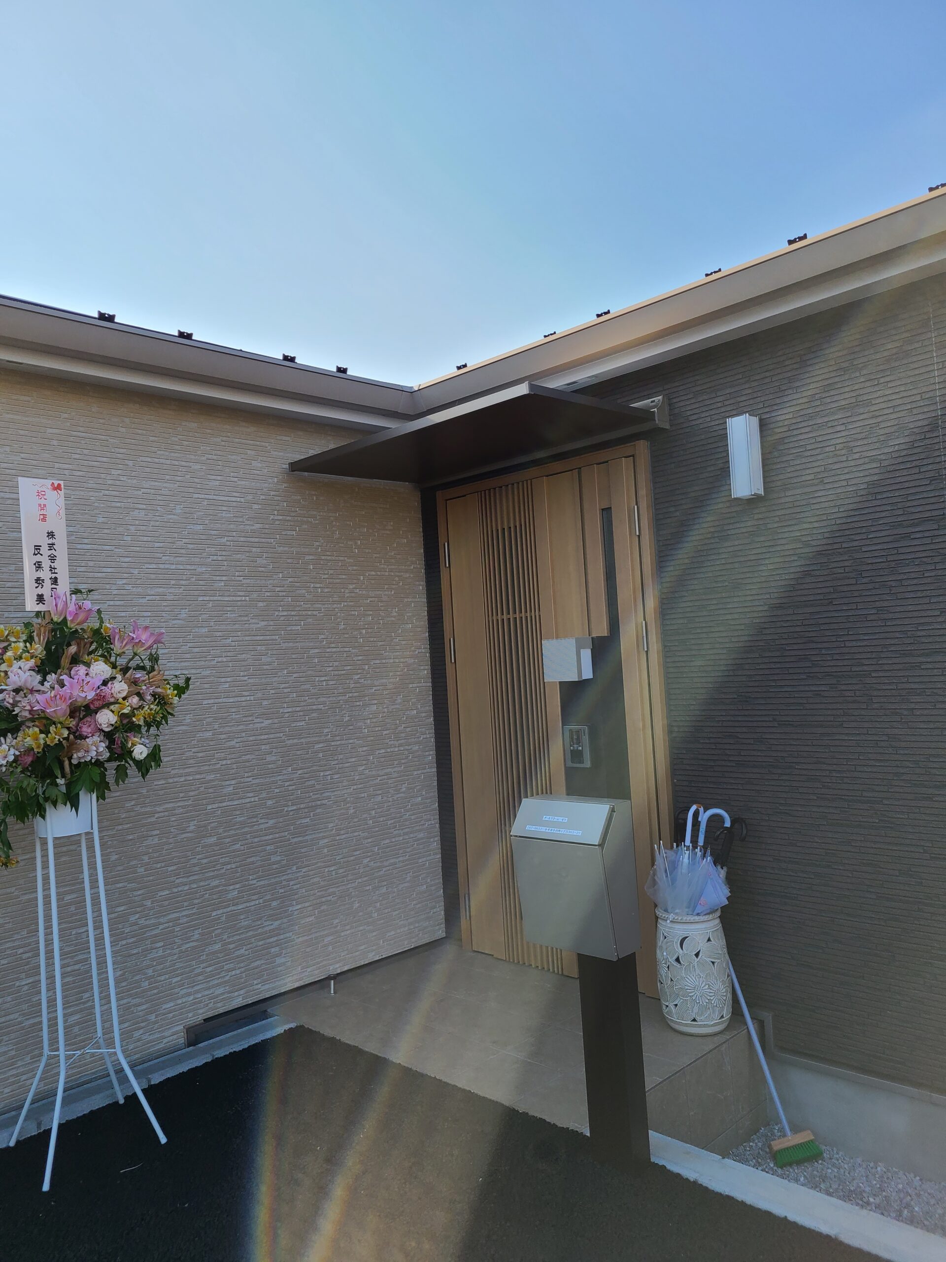 事業所の表札と美しい花が飾られた、モダンで落ち着いた雰囲気の玄関