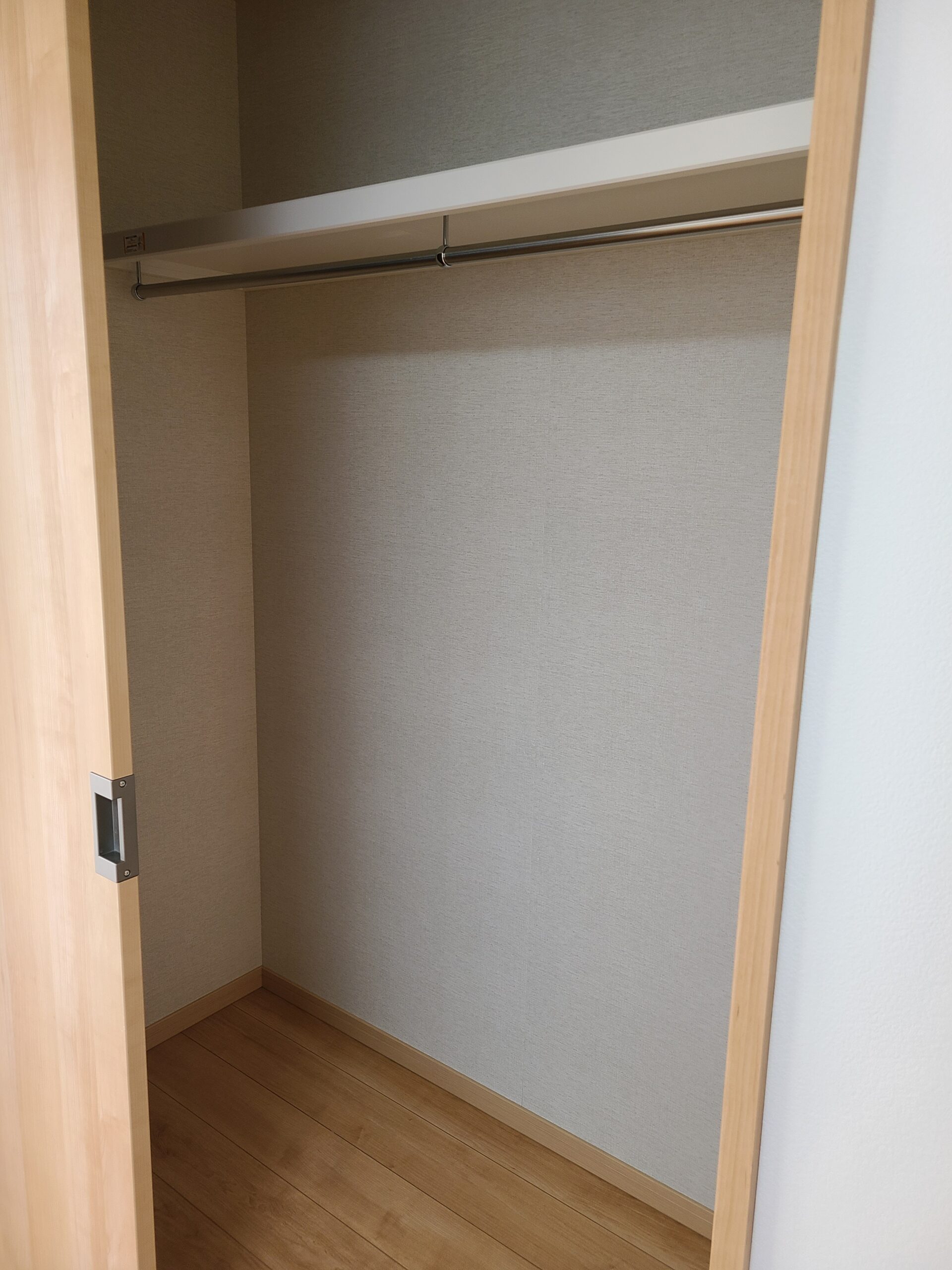 ハンガーパイプと枕棚が設置された、奥行きのあるクローゼット内部